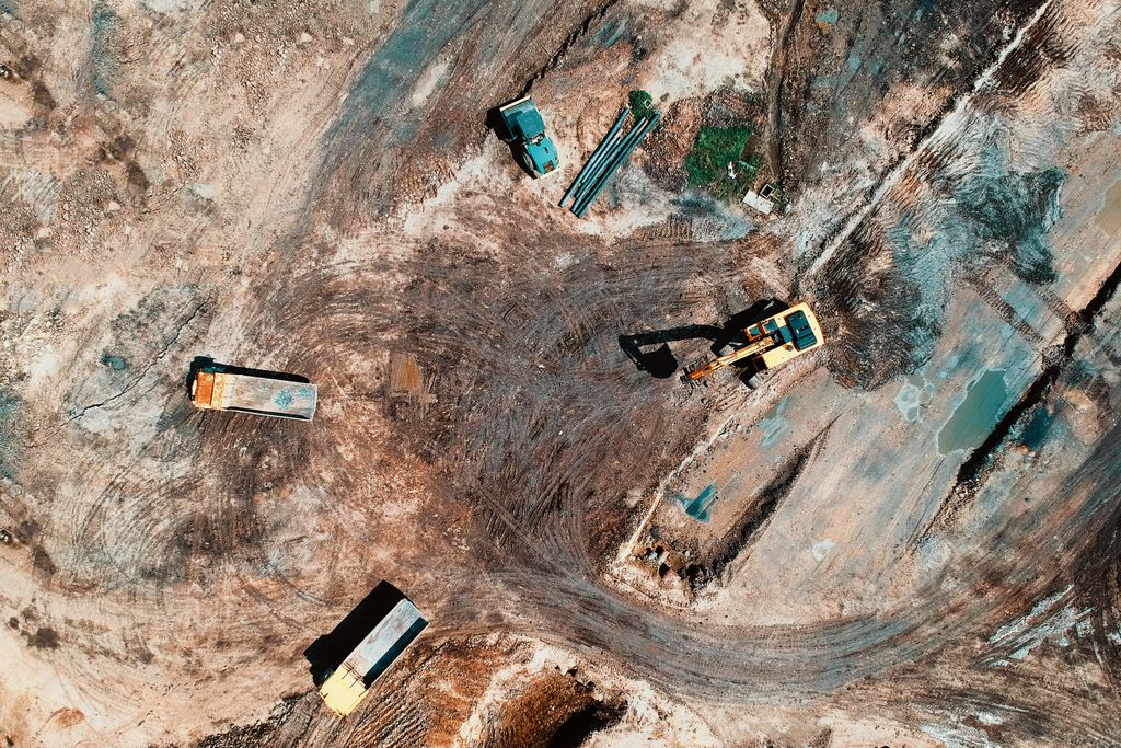 loans against development land, High-angle aerial view of construction site with earthmoving equipment and trucks.